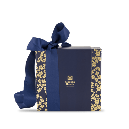 Manuka honey MGO 400+ gift set with spoon in blue gift box with gold floral patterns and a blue ribbon, featuring the Manuka Health logo.