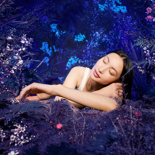 Woman lying on a bed of violet flowers. 