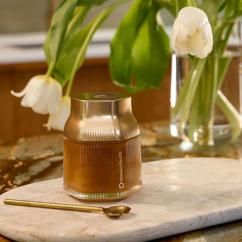 Manuka Health's Reserve MGO 1000+ Manuka Honey sitting on a counter with metal spoon.